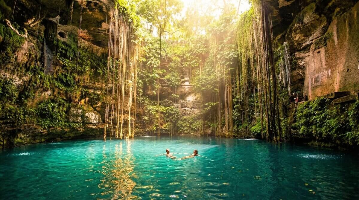 Personas flotando en el agua del Cenote Ik Kil bajo la luz del sol