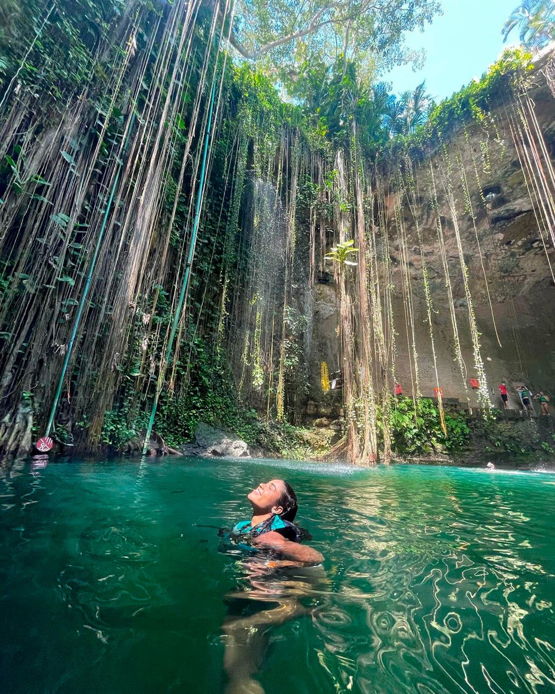 Nadador en el Cenote Ik Kil entre lianas