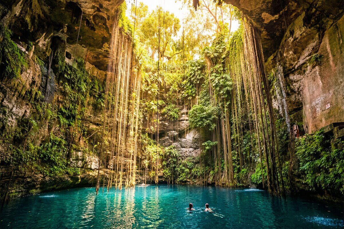 Cenote Ik Kil visto desde la orilla, con lianas colgantes y agua turquesa