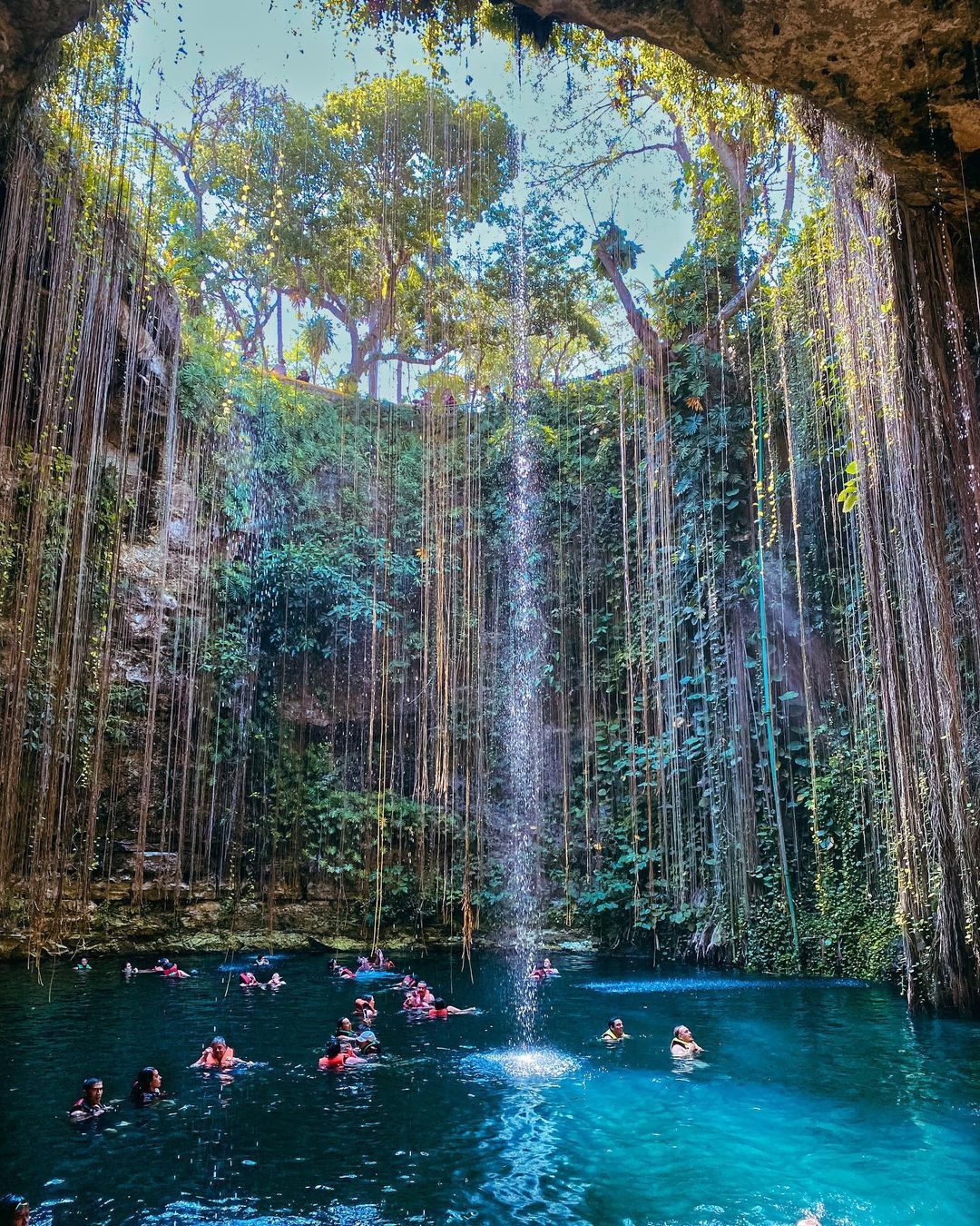 Panorama of Cenote Ik Kil with falling water and vines