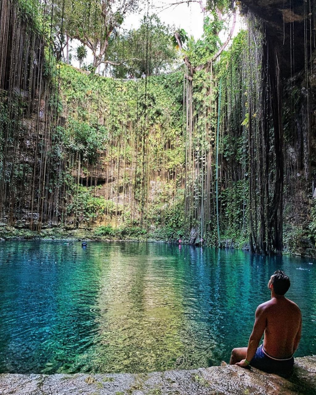 Visitante sentado frente al agua del Cenote Ik Kil